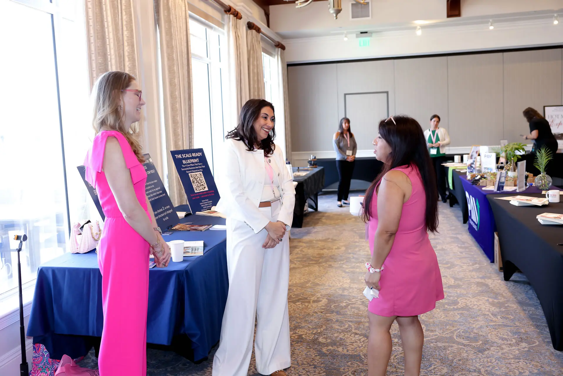 Leslie Alvarez smiling and engaging in a personal conversation with attendees at a professional networking event.