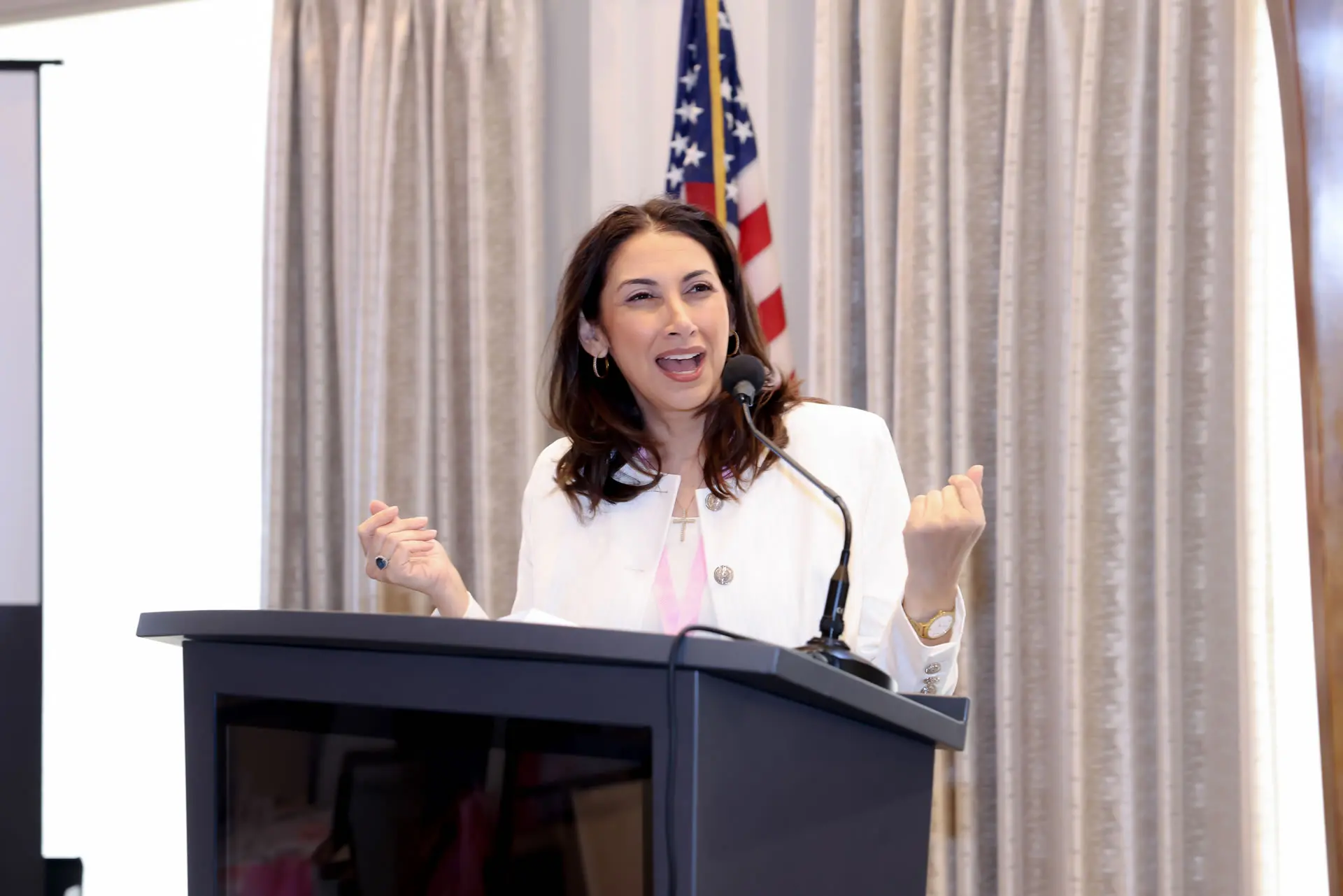 Leslie Alvarez delivering an energetic and passionate presentation, gesturing with her hands to emphasize a point while speaking at a podium.